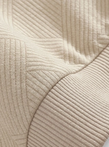 Macro detail of men's knit sweater showing premium geometric texture and beige wool fabric