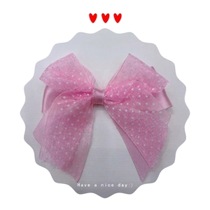 Close-up of a pink polka dot organza hair bow with silk ribbon on white card