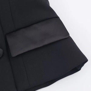 Detail aus schwarzem Webstoff und Satin-Taschenklappe an der Neckholder-Frackweste
