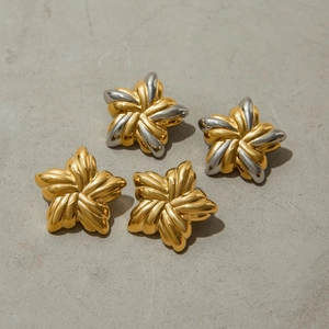 Detail of star-shaped earrings in gold and silver finish on grey stone surface