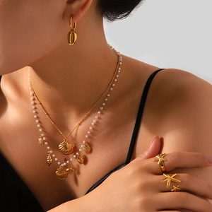 Close-up of ocean-themed jewelry set with golden seashells and starfish on model