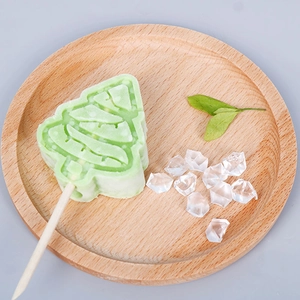 Christmas tree shaped light green silicone ice cream mold with wooden stick on tray