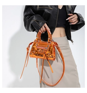 Detail of metallic orange biker bag with silver studs and long leather tassels