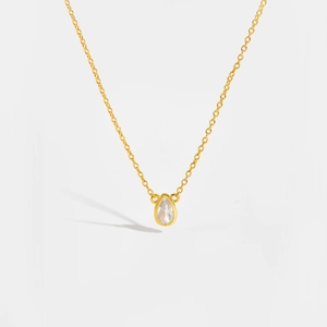Macro shot of gold teardrop pendant with clear zircon on fine silver chain