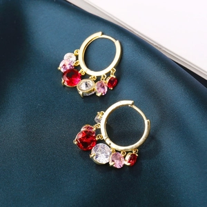 Detail of gold hoop earrings with multi-colored gemstone drops on silk fabric