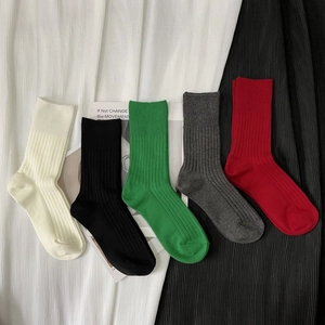 Flat lay of five pairs of ribbed cotton blend socks in ivory, green, black, red, and grey