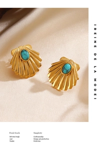 Detail of gold shell earrings with turquoise stone on elegant beige satin fabric background