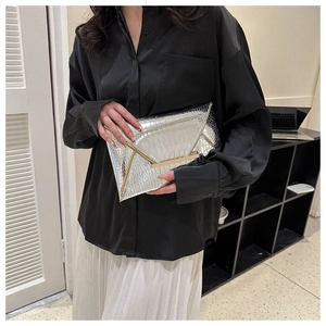 Detailed view of silver crocodile embossed clutch with elegant gold metal buckle clasp