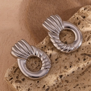 Macro detail of silver geometric earrings with irregular spiral texture on stone base