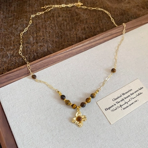Detail of vintage gold necklace with flower pendant, tiger eye beads and OT toggle clasp