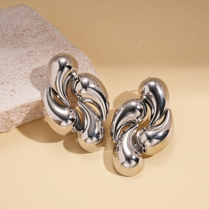 Macro shot of silver metallic irregular twisted teardrop earrings on marble stone