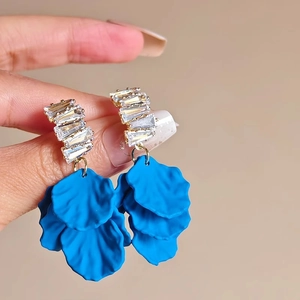 Détail de boucles d'oreilles pendantes avec cristaux brillants et pétales bleu marine