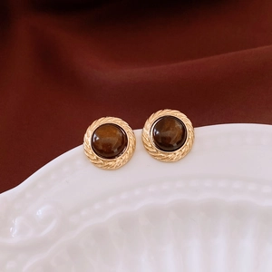 Close-up of retro round brown resin stud earrings with textured gold-tone metal borders
