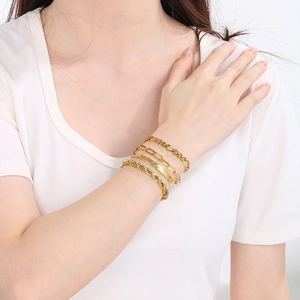 Detail of four layered gold-tone chains including cuban and paperclip styles on wrist