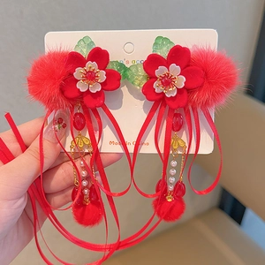 Detail of red floral hair clips with soft pom poms and elegant long tassels for girls