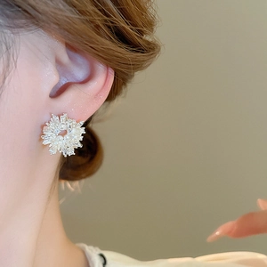 Close-up of snowflake silver earrings featuring sparkling zircon and elegant white pearls