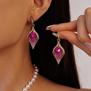 Detail view of gold teardrop earrings with rose red gemstone and crystal rhinestones