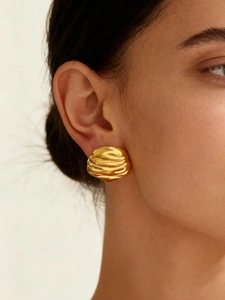Detail of 18k gold plated stainless steel earring with irregular pleated texture on ear