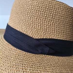 Nahaufnahme von beigem Strohgeflecht und verdrehtem dunkelblauem Stoffband-Detail