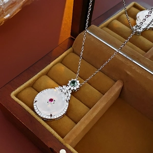 Macro detail of round white jade pendant with red gemstone and zircon inlay in jewelry box