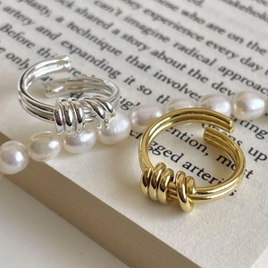 Minimalist twisted knot open rings in gold and silver finish on a vintage book