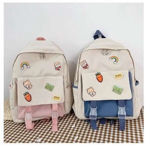 Detail showing dual buckle flap and cute cartoon badges on the canvas backpack