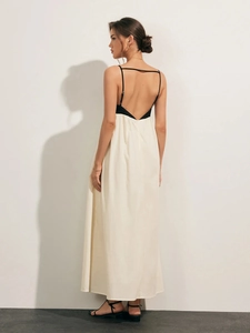 Detail view of backless color-block maxi dress with slim black straps on white fabric