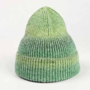 Close-up of green gradient knit beanie showing thick ribbed texture and wide folded cuff