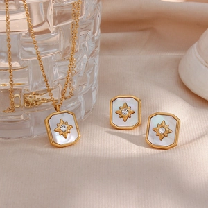 Retro star necklace and earring set with mother of pearl inlay on beige fabric background