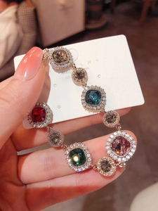 Detail of S925 silver gold-plated bracelet with multi-colored gemstones held by hand
