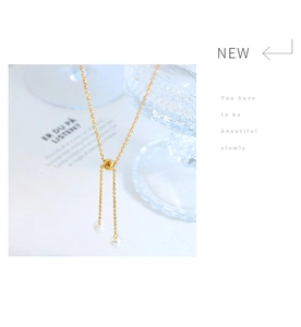 Detail view of gold adjustable sliding chain with dual pearl pendants and gold bead clasp