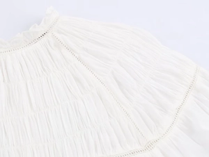 Detail of white poplin shirt featuring intricate pleated smocking and geometric lace trim