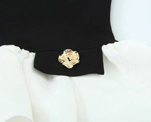 Detail of contrast patchwork top featuring a gold rose-shaped metal button accent