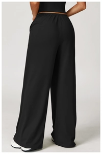 Rear view of black high-waisted wide-leg trousers showing drape and elastic waistband