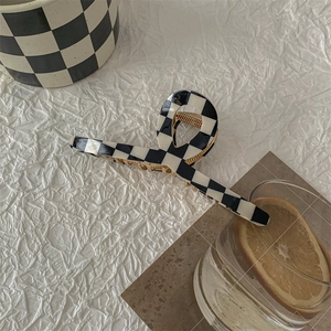Detailed close-up of a large black and white checkered hair claw clip with a gold spring