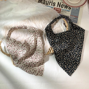 Detail showing elastic hair band with floral patterns in beige and black fabric