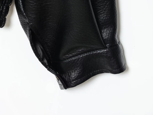 Detail of black leather sleeve with textured pebble grain and precision double stitching
