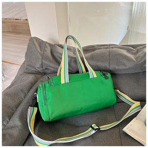 Detail of green nylon cylinder sports bag with striped straps on a gray sofa