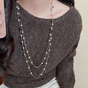 Dettaglio di una collana a doppio strato con perle occhio di tigre e perle su modella