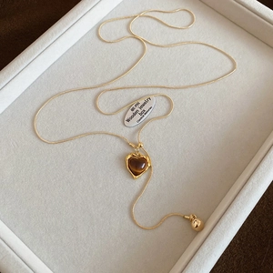 Detailed close-up of golden heart-shaped tiger eye stone pendant necklace on velvet tray