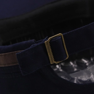 Detail of adjustable metal buckle and leather strap on navy blue cotton twill cap