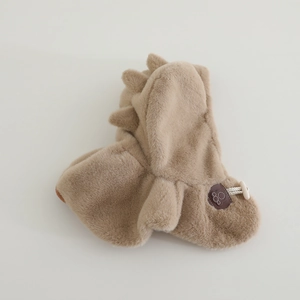 Dettaglio macro del cappello dinosauro in peluche marrone con pelliccia e etichetta in pelle