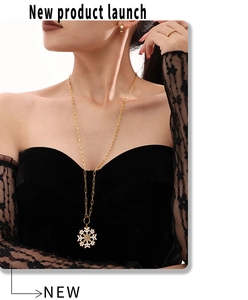 Detail of a gold snowflake pendant necklace with crystal zircons on a model in black attire
