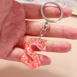 Detailed view of resin letter S keychain with vibrant orange sequins and metal ring