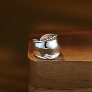 Anello largo lucido con design a onde in finitura argento su base di legno