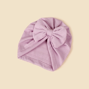 Macro detail of lavender waffle knit baby turban hat featuring a large handmade bow decoration