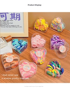 Colorful ruffled hair ties set in a heart-shaped transparent gift box on a wooden desk