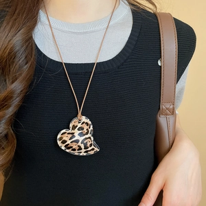 Close-up of leopard print heart pendant with vintage leather cord and stitching detail