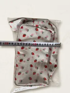 Close-up of a corduroy strawberry bag width measurement showing size details on a wooden table