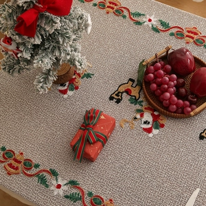 Close-up of Christmas embroidery detail on beige lace tablecloth with festive motifs